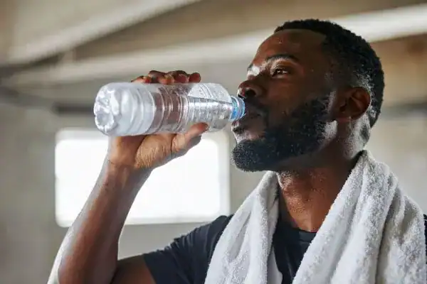 Image of man drinking water to improve hydration Brighton after work out.